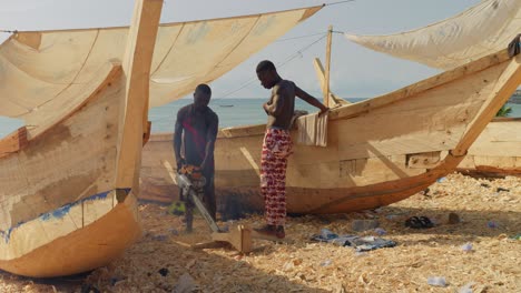 Black-african-carpenters-working-on-new-wooden-boats-with-chainsaw
