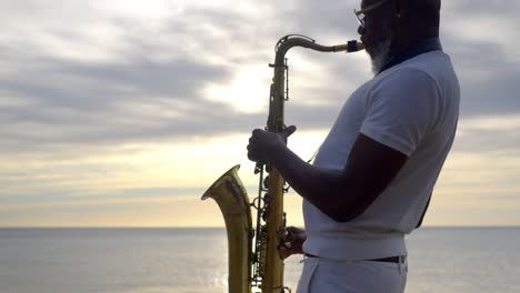 Szenische-Aufnahme-Eines-Saxophonisten,-Der-Bei-Sonnenuntergang-Am-Strand-Saxophon-Spielt