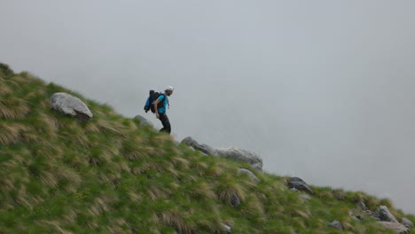 Male-Hiker-Rushing-Down-Along-Mountain-Ridgeline-In-Valmalenco-On-Overcast-Day