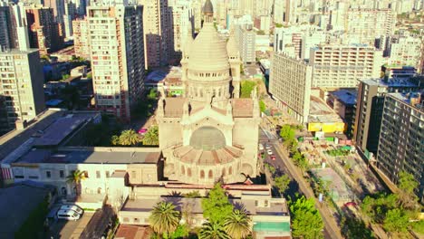 Luftaufnahme-Zur-Darstellung-Der-Neigung-Der-Kirche-Los-Sacramentinos-In-Einem-Wohnviertel-Mit-Der-Bergkette-Im-Hintergrund,-Santiago,-Chile