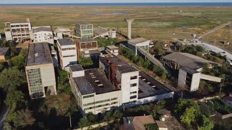 Drone-overview-of-forsaken-factory-in-Romania,-Black-sea-in-the-background