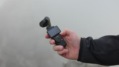 -DJI-Osmo-Pocket-3-Wird-In-Der-Hand-Gehalten-Und-Der-Bildschirm-Wird-Gedreht,-Um-Das-Gerät-Einzuschalten