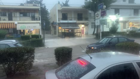 Heavy-rain-ob-streets-of-Kifissia,-Athens,-Greece-view-through-a-moving-bus-window