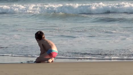 Young-boys-playing-on-the-beach-throwing-the-sand-in-the-water-and-running-around