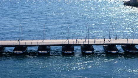 Un-Dron-Desciende-Mientras-Los-Peatones-Cruzan-El-Puente-De-Pontones-Reina-Emma