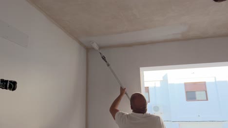 La-Persona-Está-Usando-Un-Rodillo-De-Pintura-Y-Agregando-Pintura-A-La-Superficie-Del-Techo-De-La-Pared,-Comerciante-Responsable-De-La-Pintura-Y-Decoración-De-Edificios.