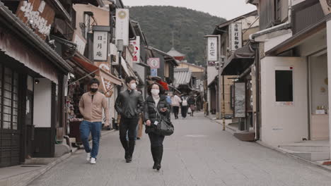 Few-tourists-and-local-in-masks-strolling-the-streets-and-alleys-in-the-historical-area-near-Ninenzaka-in-Higashiyama,-Kyoto-in-Japan-in-winter-during-Covid-19