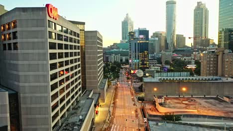 Aerial-establishing-shot-of-CNN-Building-with-cars-on-road-and-Skyscraper-Towers-of-Atlanta-City-in-background-at-sunset-time