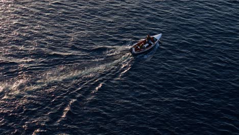 Fishermen-return-home-as-sunset-light-glistens-across-deep-dark-blue-ocean-water