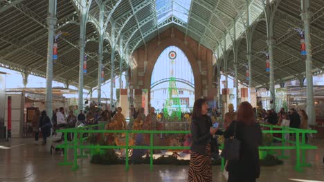 People-visiting-the-large-nativity-scene-Christmas-setup-at-the-Market-de-Colon-in-Valencia,-Spain