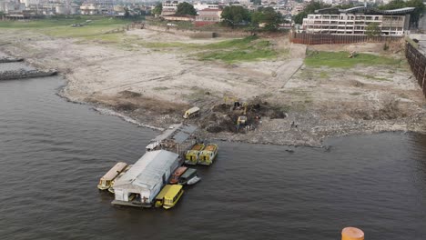 Aerial-drone-shot-of-Manaus,-Amazon,-Brazil:-Environmental-crime,-garbage-cleaning-by-big-tractors-on-river-edge