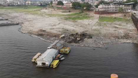 Toma-Aérea-De-Drones-De-Manaos,-Amazonas,-Brasil:-Delitos-Ambientales,-Limpieza-De-Basura-Con-Grandes-Tractores-A-Orillas-Del-Río