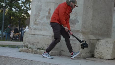 Camarógrafo-En-Acción-Con-Técnica-De-Disparo-En-ángulo-Bajo-Utilizando-Un-Cardán-Estabilizador-Dji-Ronin-Rs3-Con-Una-Cámara-Profesional-Montada-Caminando-Por-Las-Calles-De-La-Ciudad