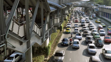 Man-Sieht-Menschen,-Die-Den-Erhöhten-Fußweg-Von-Einer-Station-Zur-Anderen-Und-Dann-Zu-Den-Bahnsteigen-Benutzen,-Während-Die-Straße-Auf-Der-Rechten-Seite-Bereits-Verstopft-Und-Dennoch-Fließend-Ist,-Bangkok,-Thailand