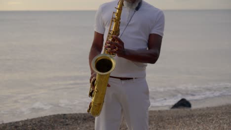Mann-Spielt-Saxophon-Am-Meeresufer-In-Der-Abenddämmerung