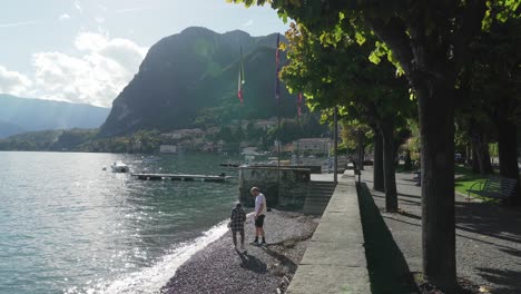 Pareja-Joven,-Arrojar,-Rocas,-En,-Lago-Como,-En,-Ciudad,-De,-Menaggio