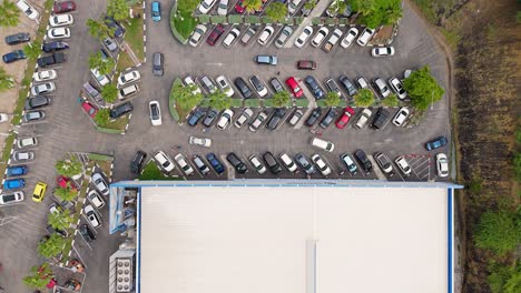 Aerial-top-down-static-view-of-cars-circling-in-parking-lot-of-supermarket-store