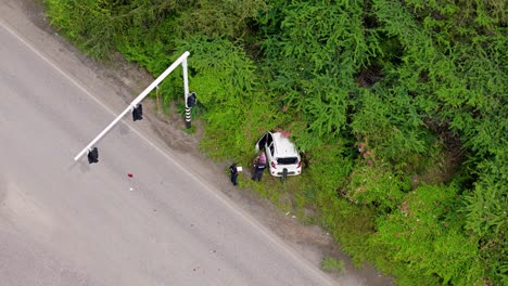 Aerial-orbit-around-policeman-surveying-situation-of-car-crashed-into-tropical-jungle