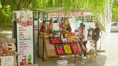 Durstige-Touristen-Kaufen-Kalten,-Frischen-Saft-Am-Türkischen-Dorfmarktstand