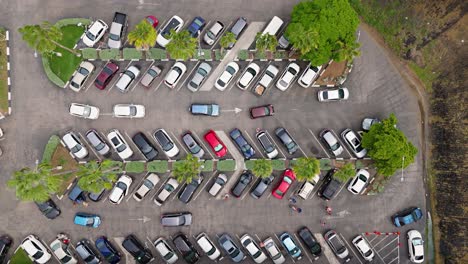 Drone-top-down-trucking-pan-above-cars-circling-in-parking-lot-of-supermarket