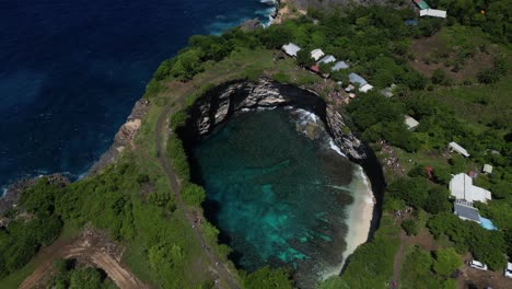 A-hole-of-water-surrounded-by-cliffs-and-greenery-in-Nusa-Penida-Island,-near-Bali