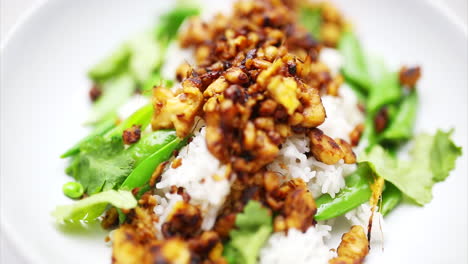 Stir-fried-Tempeh-rotating-on-a-plate-with-green-vegetables-and-white-rice