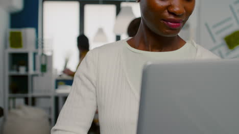 Mujer-Africana-Mirando-La-Cámara-Sonriendo-De-Pie-En-La-Puesta-En-Marcha-De-Una-Agencia-Creativa