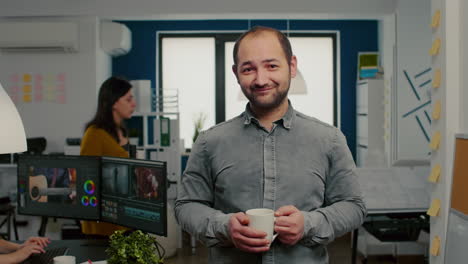 Portrait-of-videographer-standing-in-front-of-camera-smiling