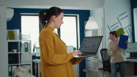 Portrait-of-business-woman-posing-casual-holding-laptop-with-finanical-data-typing-and-smiling-at-camera