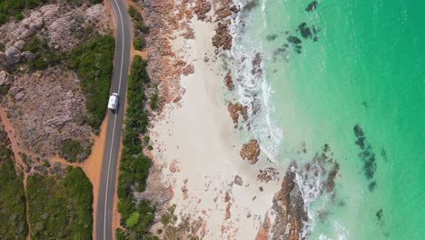 Cinematic-top-down-view-of-motorhome-driving-along-scenic-coastal-road-in-Margaret-River,-Western-Australia-at-high-tide