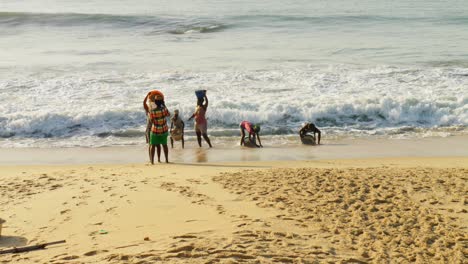 Afrikanische-Dorfbewohner-Sammeln-Strandsand-In-Körben-In-Großen-Meereswellen