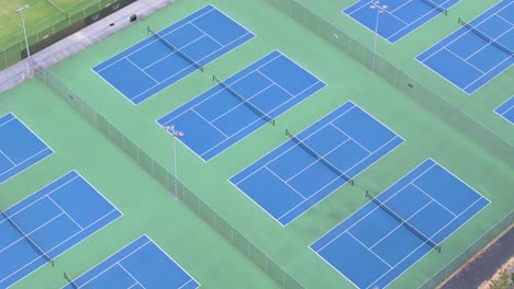 Bright-coloured-tennis-courts-seen-from-drone-view-above-at-sunset