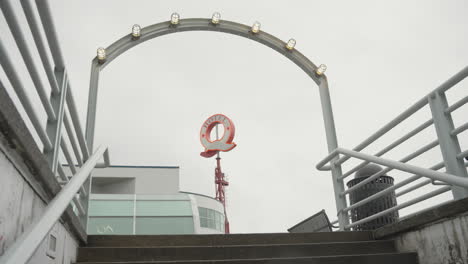 A-dolly-shot-moves-through-an-opening,-revealing-a-Q-shaped-neon-sign-that-reads-'Hotel