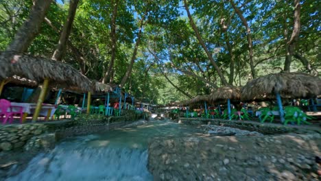 Vuelo-FPV-Sobre-El-Río-Con-Niños-Jugando-Y-Restaurante-En-El-Balneario-San-Rafael-En-Barahona