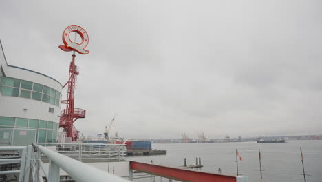 An-upward-boom-shot,-with-a-railing-in-the-foreground,-captures-a-Q-shaped-Hotel-sign-against-the-backdrop-of-the-ocean-on-a-rainy,-dreary-day