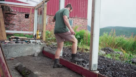 A-Man-is-Using-His-Feet-to-Compact-the-Rocks-for-the-Construction-of-the-Greenhouse---Close-Up