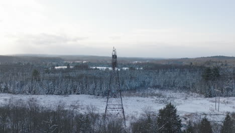 Torre-Eléctrica-De-Alta-Tensión-En-Un-Bosque-Nevado-De-Invierno,-Aérea