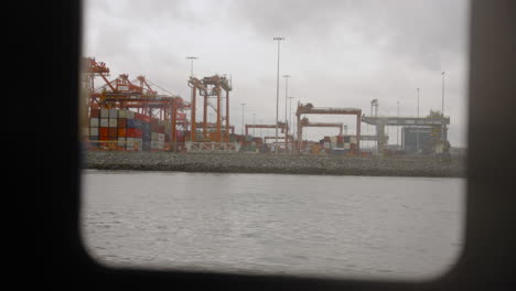 Observing-through-the-Sea-Bus-window,-glimpsing-boats,-cranes,-shipping-containers,-and-trucks