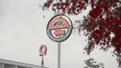 A-right-to-left-dolly-shot-unveils-a-neon-sign-reading-'Lonsdale-Quay-Market,'-with-a-smaller-Q-shaped-sign-reading-'Hotel'-in-the-background