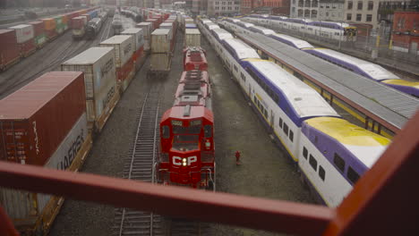 A-dolly-shot-moving-from-right-to-left,-passing-the-metal-beams-of-a-walkway,-capturing-a-Canadian-Pacific-locomotive-moving-slowly-along-the-tracks