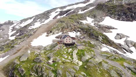 House-standing-on-a-steep-rocky-slope-partly-covered-in-snow-in-the-Alps-in-Kaernten,-Austria