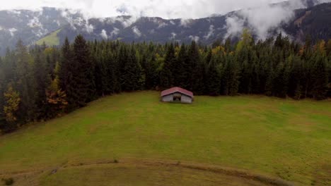 Typical-hut-in-Austria-surrounded-by-forest-trees,-Mountain-landscape,-aerial