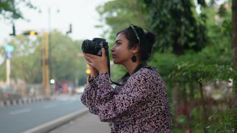 The-female-photographer-holds-a-camera-on-a-street-and-takes-a-photo