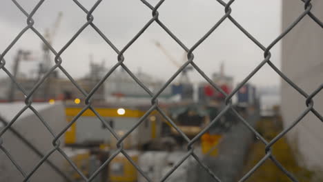 Ein-Von-Rechts-Nach-Links-Fahrender-Dolly-Erfasst-Einen-Scharf-Fokussierten-Maschendrahtzaun,-Im-Hintergrund-Ist-Das-Vancouver-Seaspan-Drydock-Verschwommen