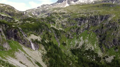 Bautiful-valley-surrounded-by-high-cliffs-and-a-waterfall-leading-down-the-cliff-in-the-Alps-in-Kaernten,-Austria