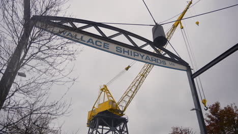 Eine-Sanfte-Dolly-Bewegung-Von-Links-Nach-Rechts-Des-Wallace-Shipyards-Schilds,-Ein-Leuchtend-Gelber-Kran-Im-Hintergrund