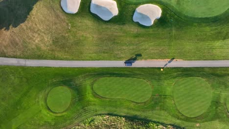 Top-down-tracking-shot-of-golf-cart-on-green-country-club-course-during-summer