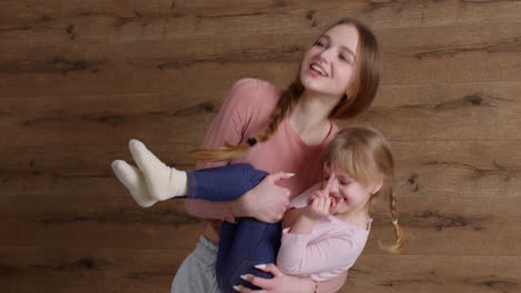 Young-lovely-mother-babysiter-and-little-kid-daughter-jumping-dancing-on-bed-in-modern-house-bedroom