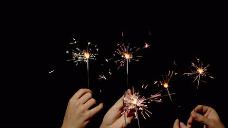 Hands-holding-and-waving-Bengal-fires.-New-year-sparkler-candle-burning-on-a-black-background