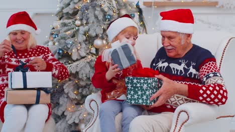 Nieta-Intercambiando-Cajas-De-Regalo-De-Navidad-Con-Un-Abuelo-Mayor-Feliz-Y-Asombrado-En-Casa